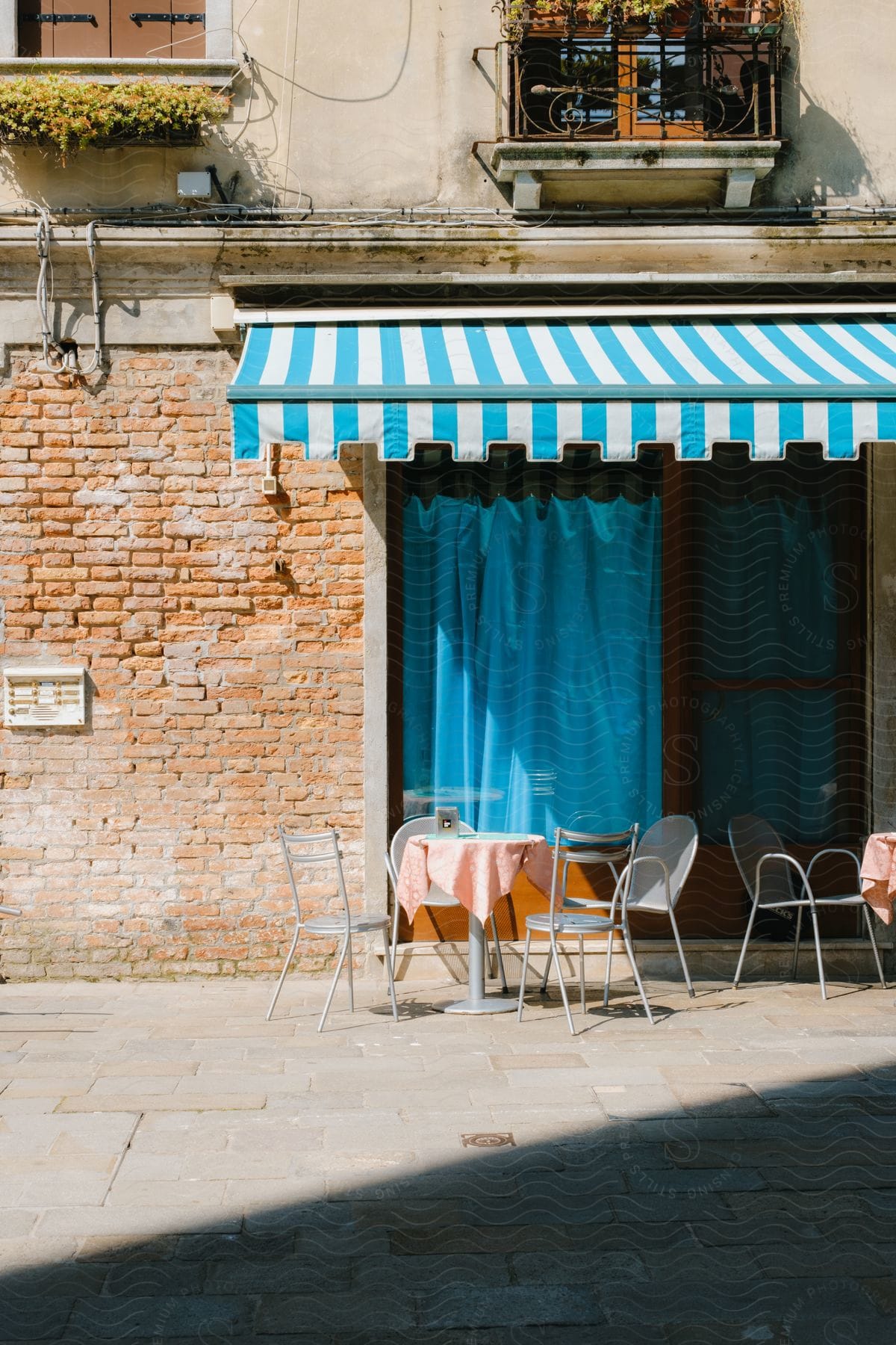 Tables and chairs outside a coffee shop on an old building, with exposed bricks.