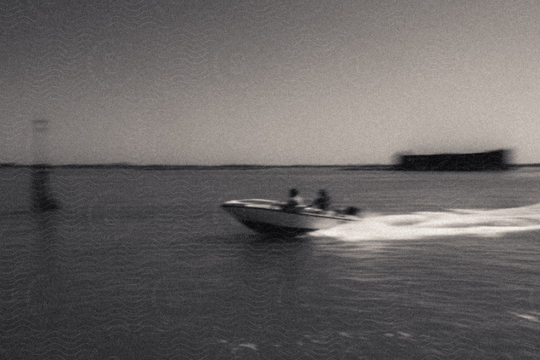 Two people in a speeding motorboat leave a white wake as they approach a buoy