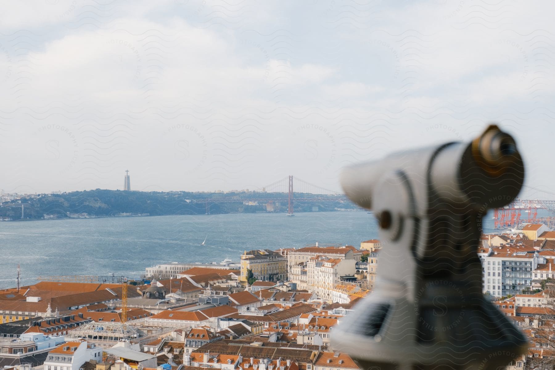 Telescope view finder focuses on water across red roofed buildings.