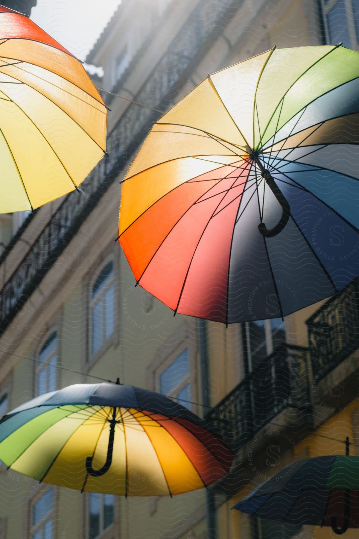 Colorful umbrellas are suspended on wires between apartment buildings in a suburb to provide additional shading from the sun in the daytime.