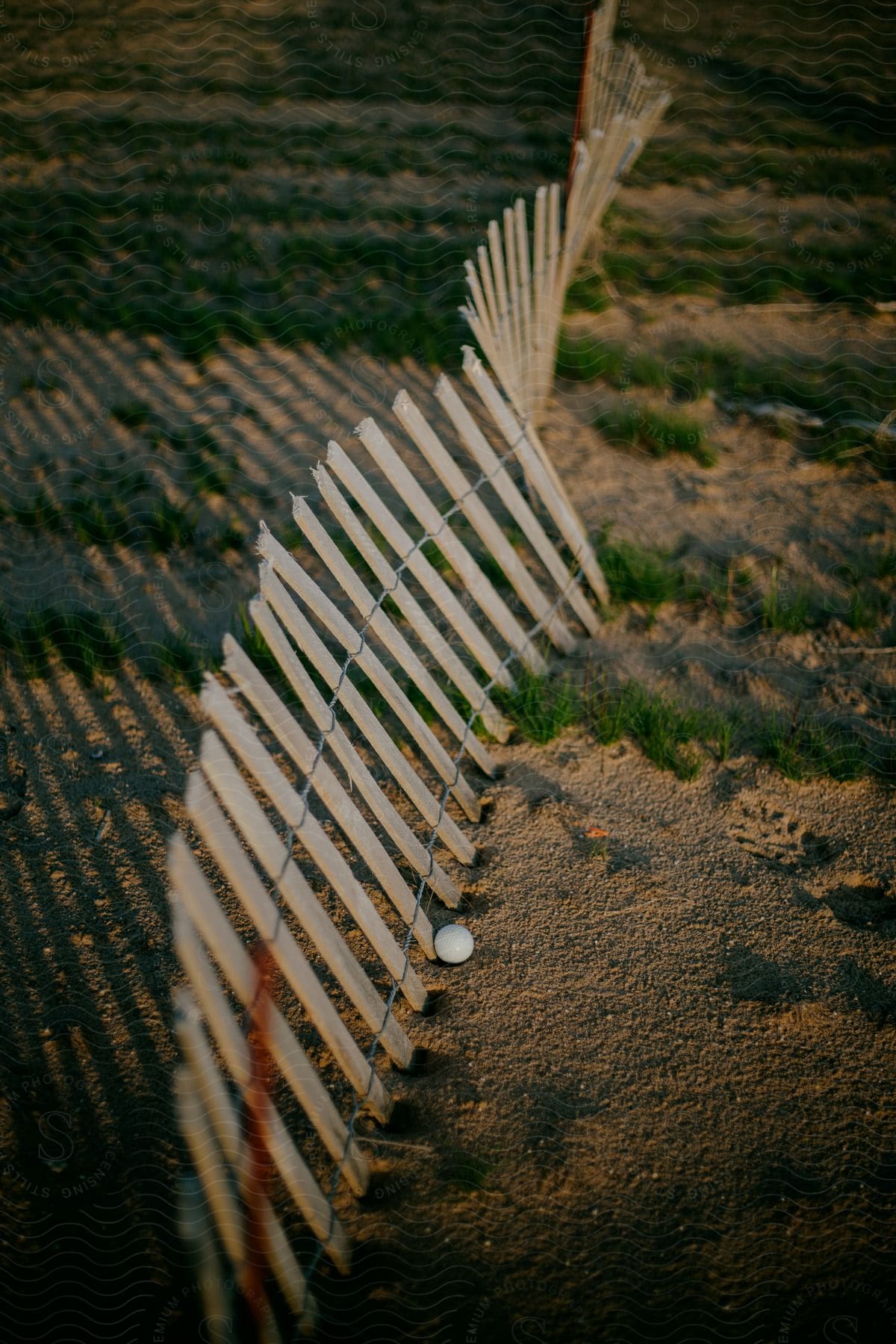 A golf ball up against a fence out on a golf course