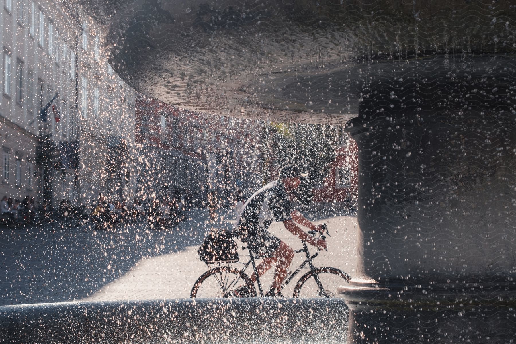 Looking through a dirty window as a man rides his bicycle through town