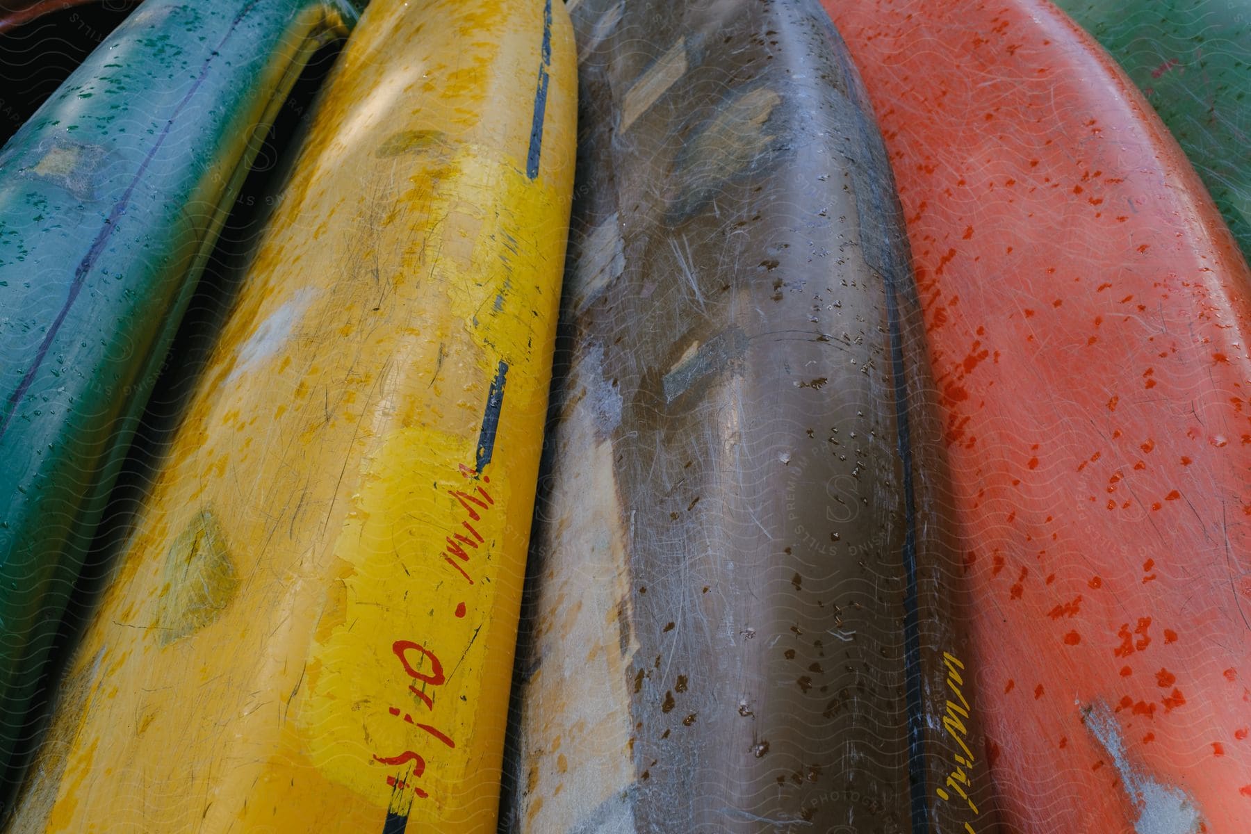 four colorful canoes which include yellow, green, brown and red are stacked on top of each other