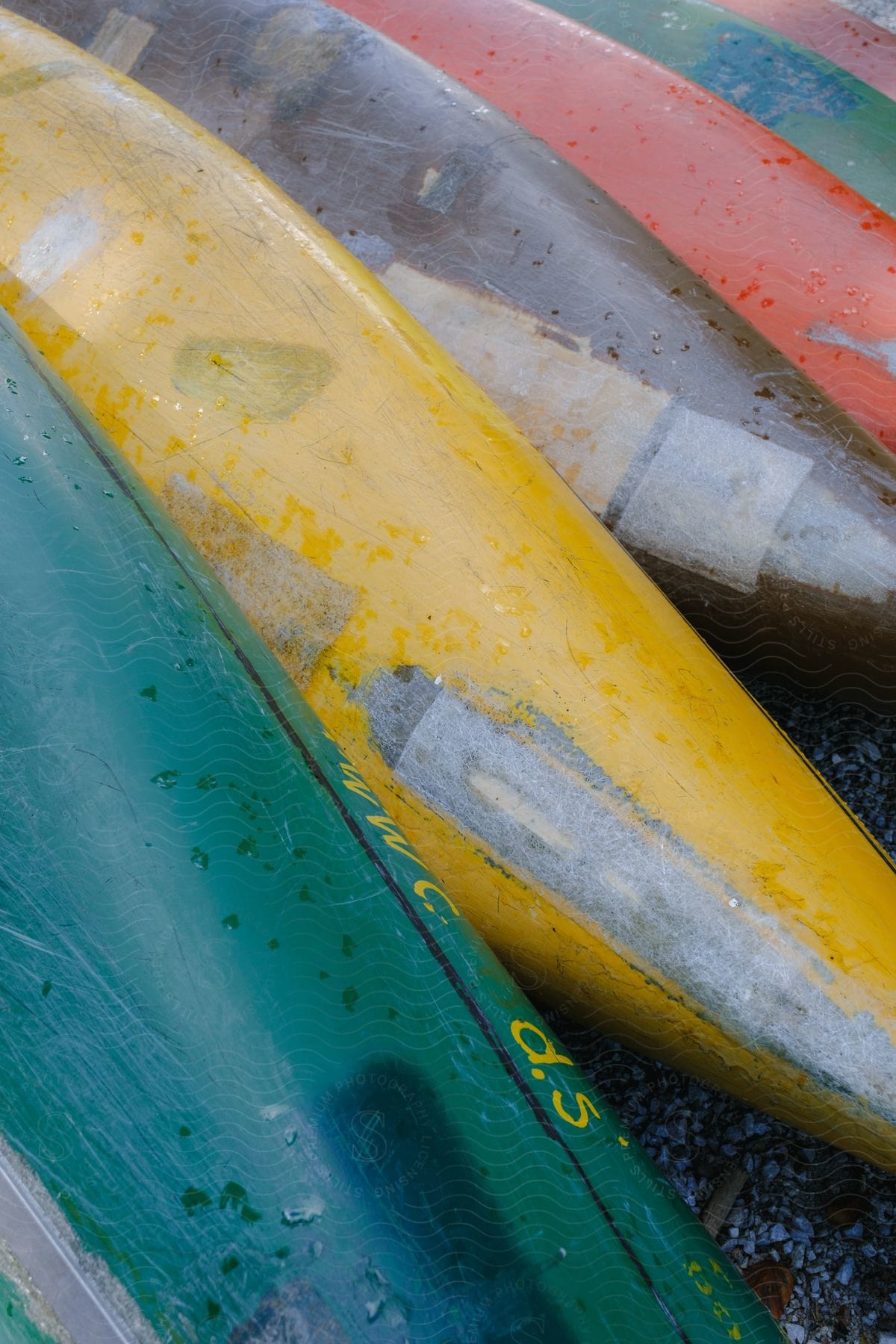 Kayaks of varying colors lined up on pebbles.