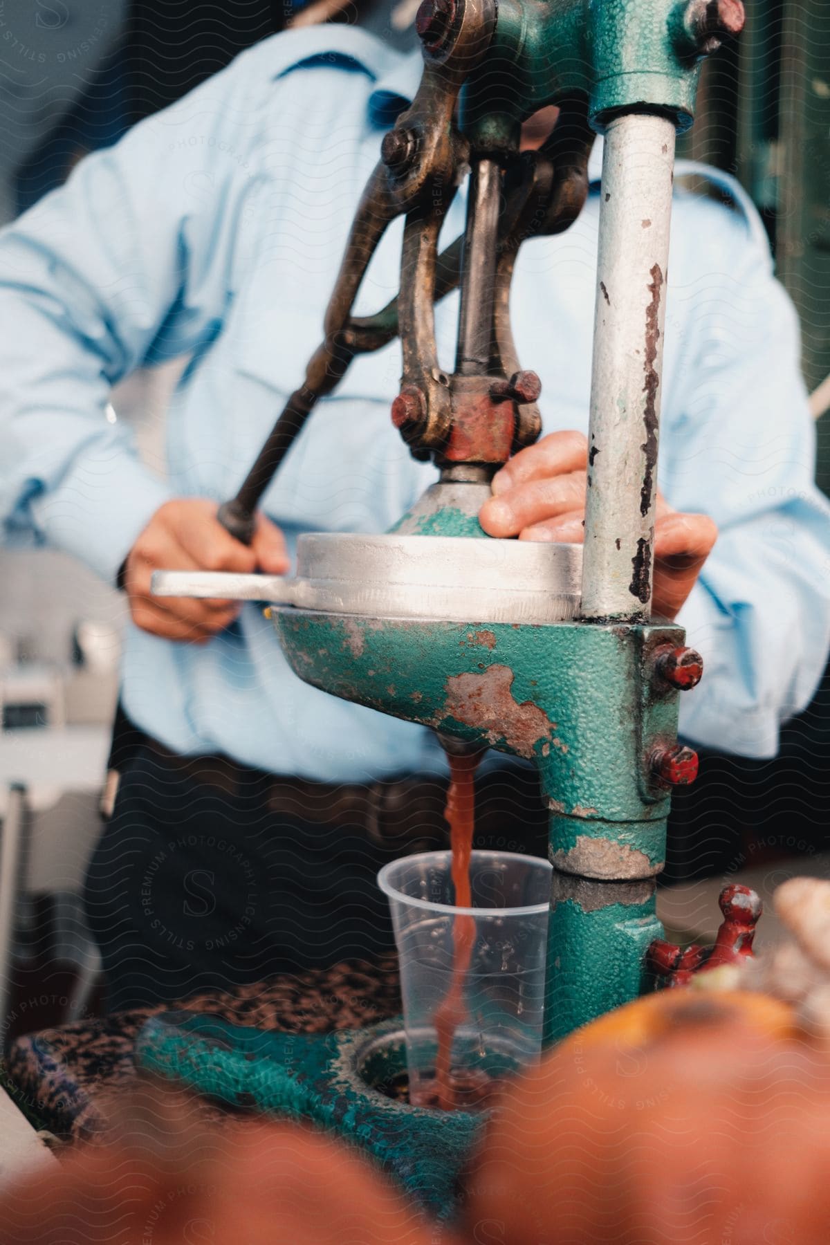 Stock photo of a man  is squeezing a fruit into  a clear cup.