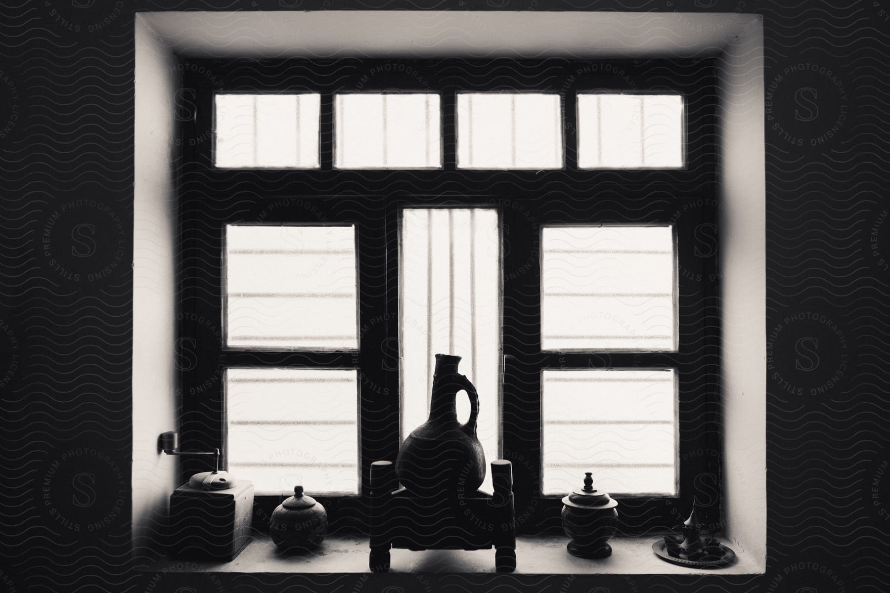 A vase on a window sill, flanked by two vases on each side, sunshine coming in through the frosted windows.