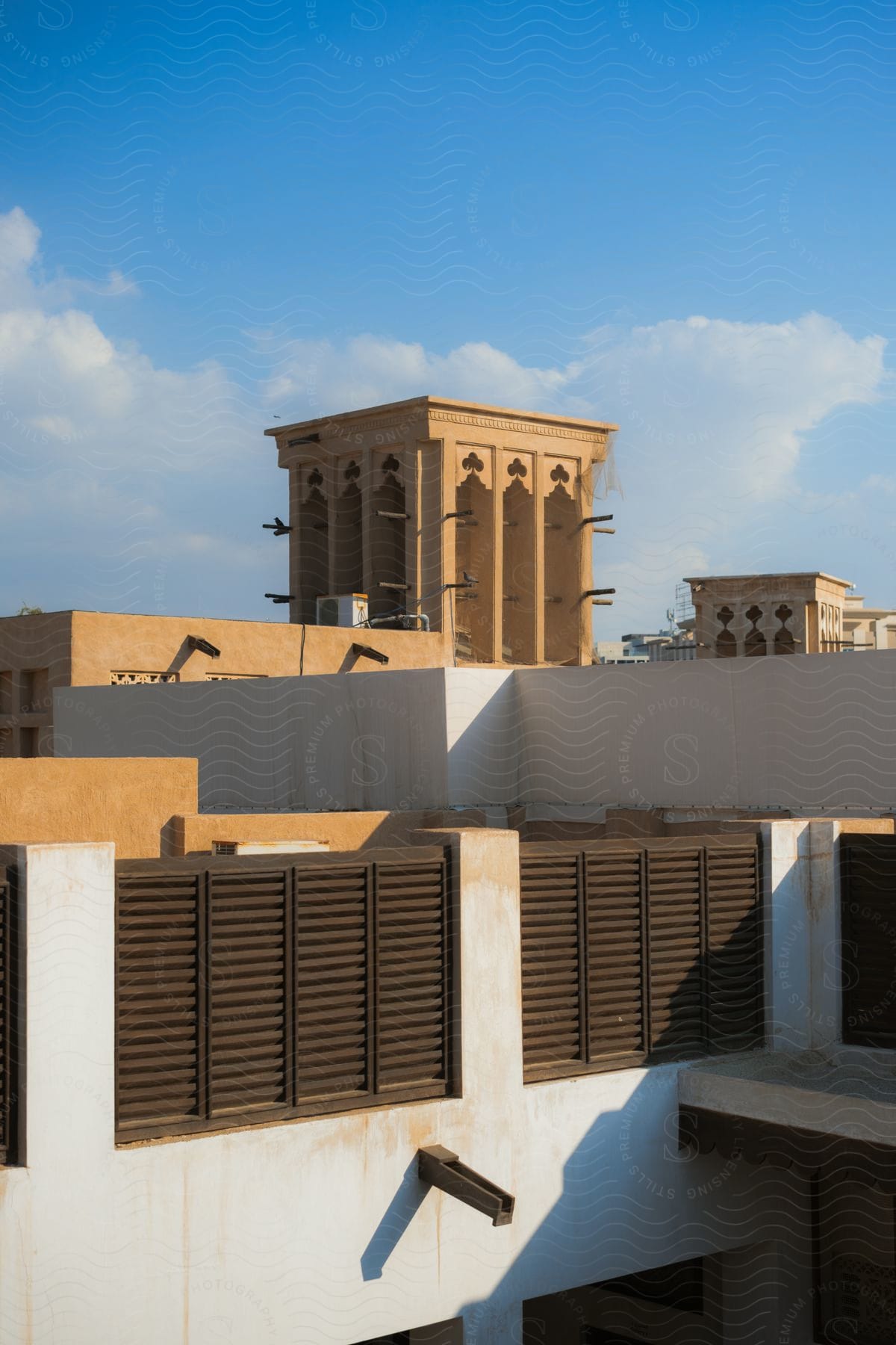 Traditional Arabic cooling wind towers stand among buildings under a cloudy sky