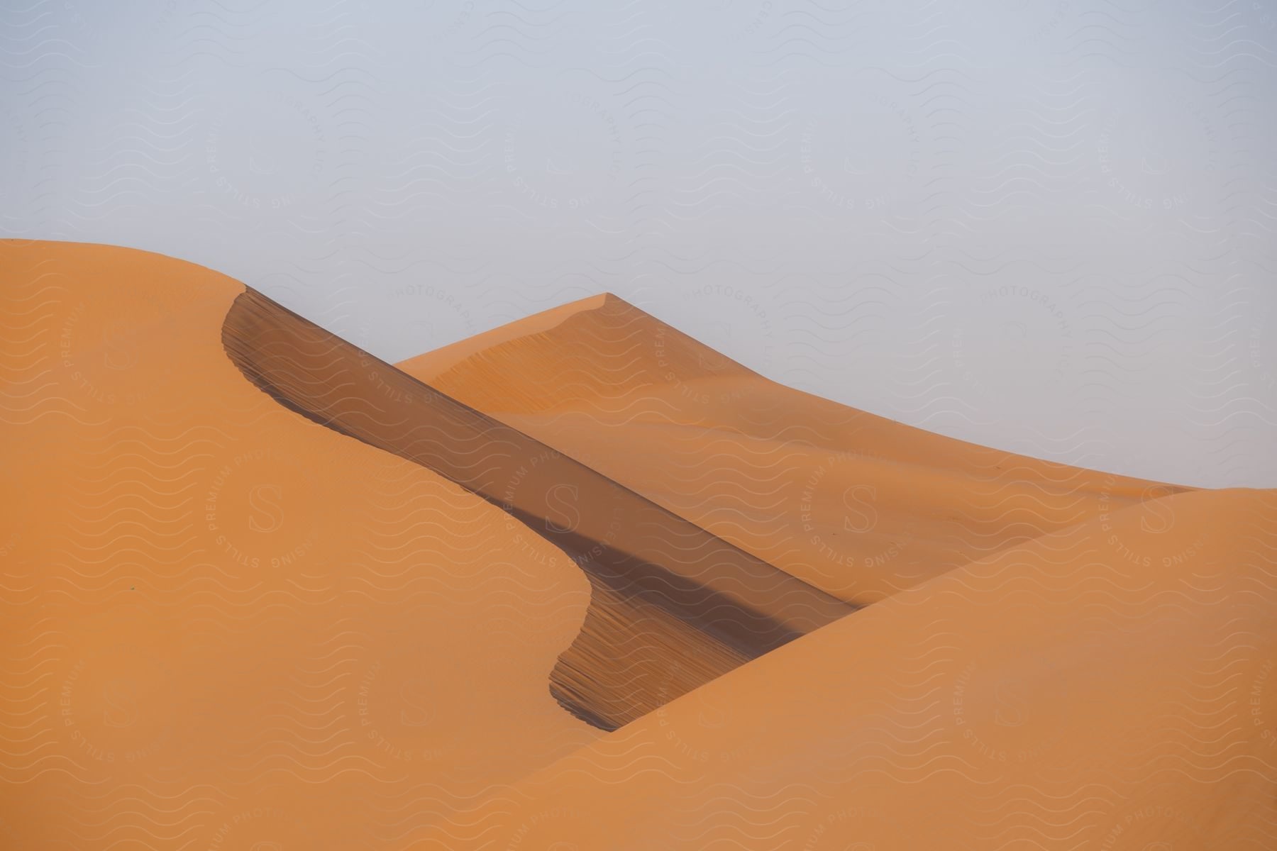 A sand dune rises from the barren desert on a sunny day.