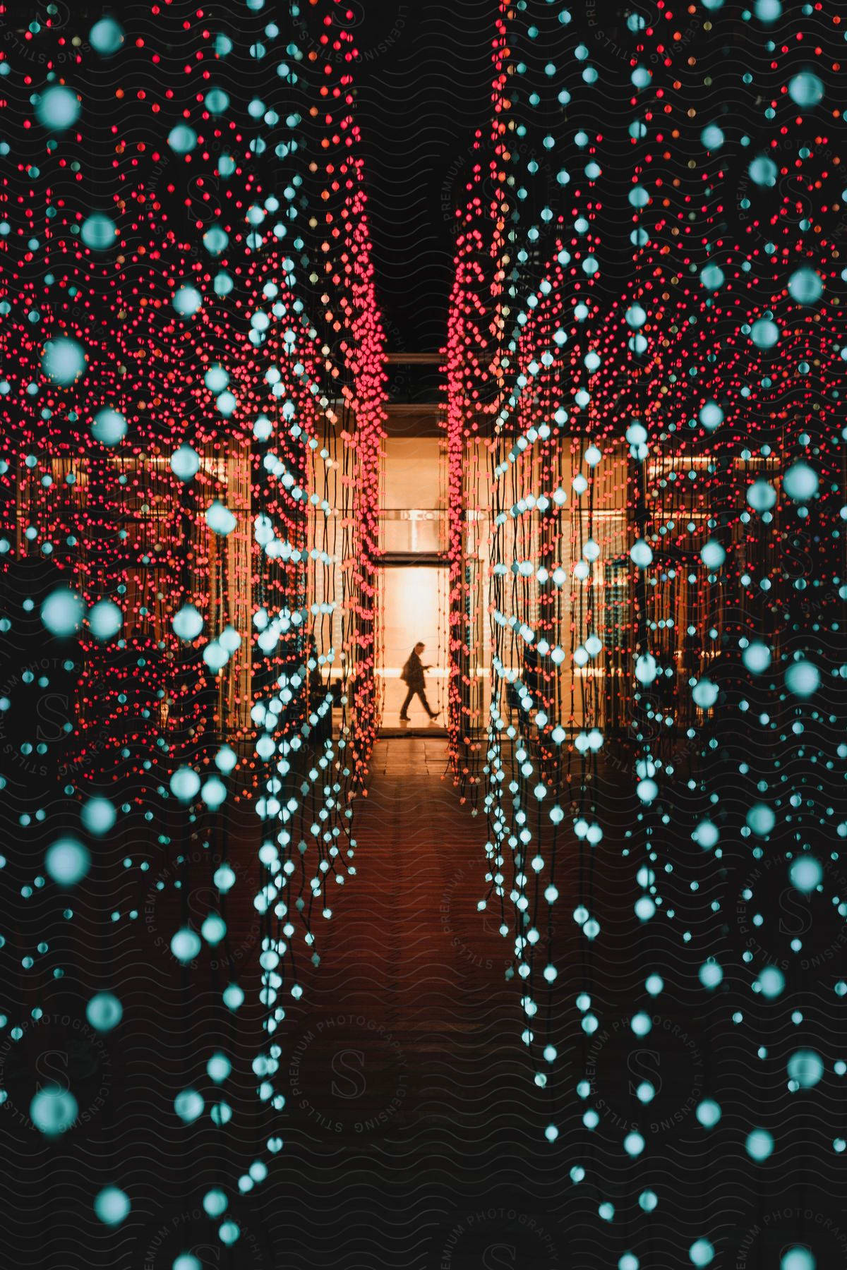 A corridor full of glowing bubbles and at the end a person walking.