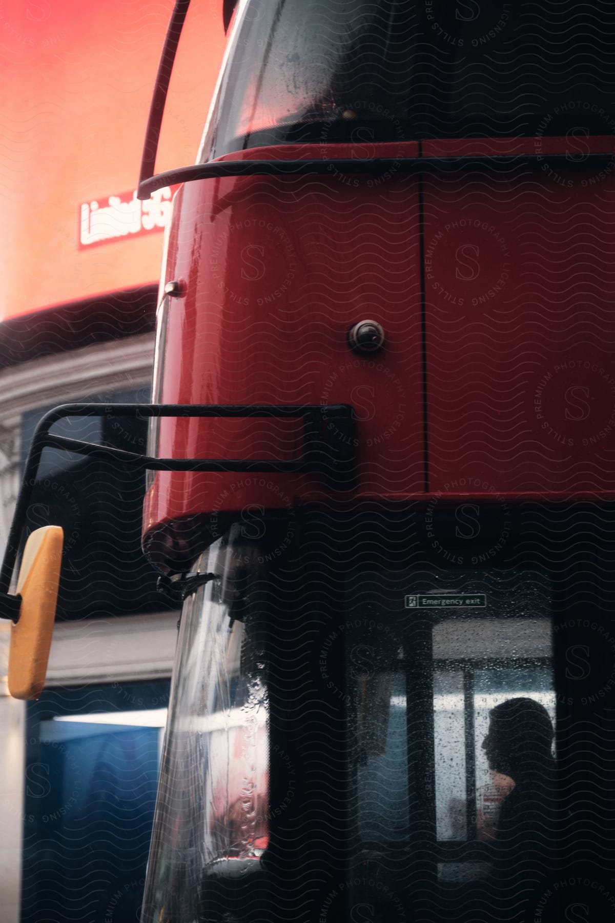 A Silhouette Of A Man Sitting Inside A Red Bus