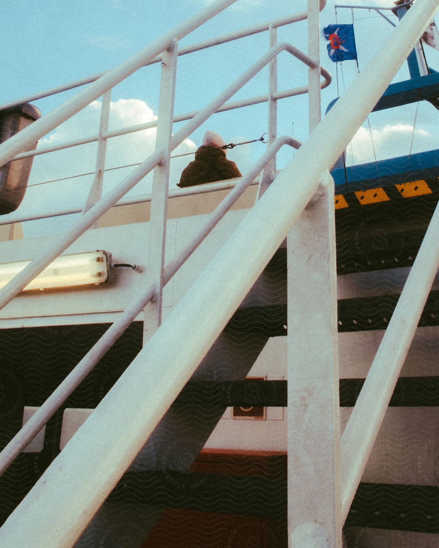 a person sits near the stairs on the upper level of a ferry