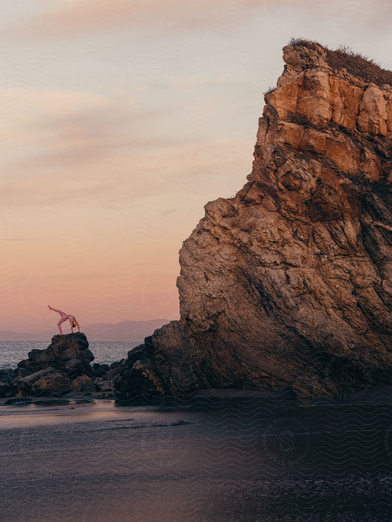 lady doing flip on the rock by the beach