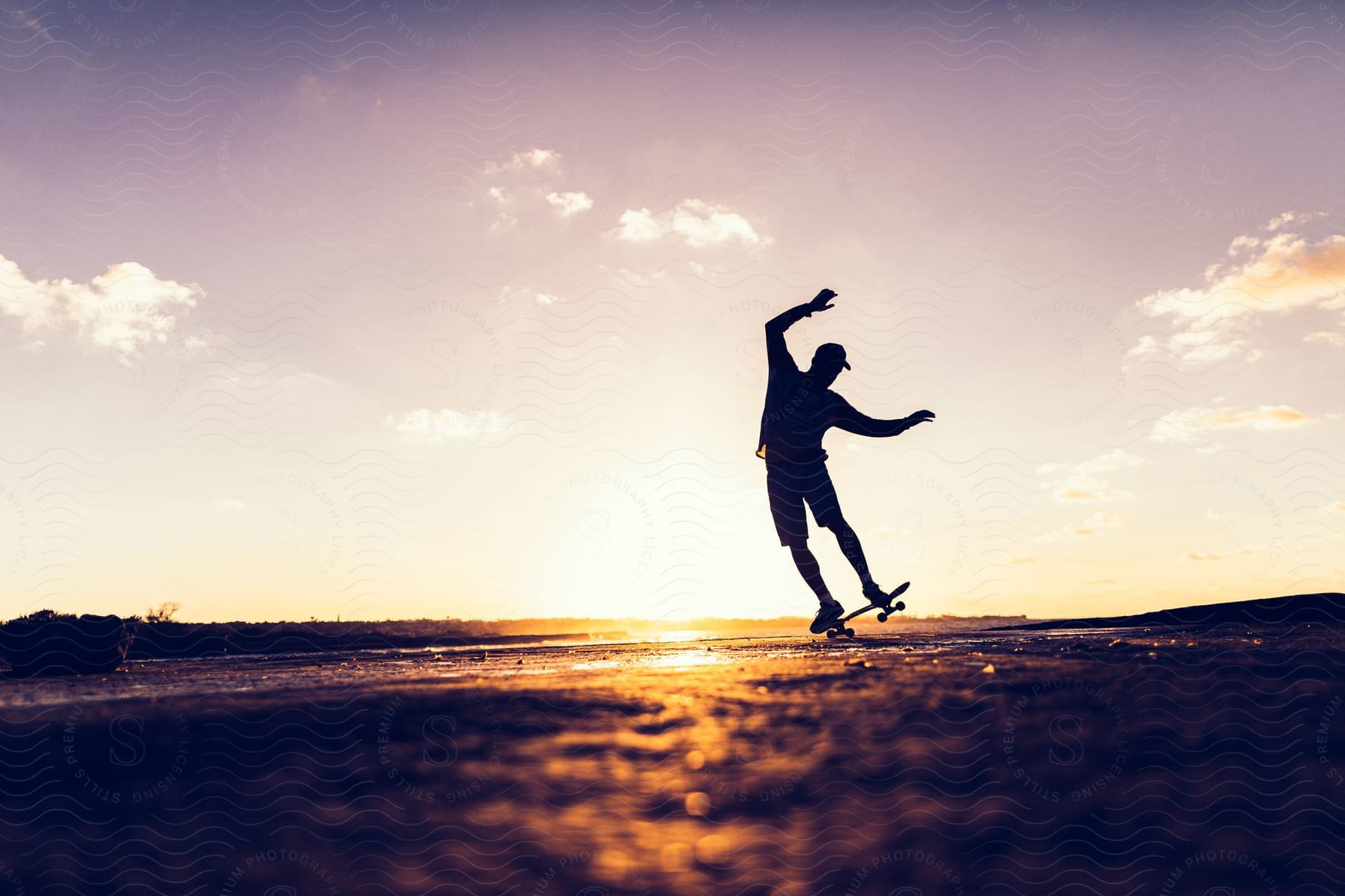 A man is skateboarding alone while being silhouetted by the sun at dusk.