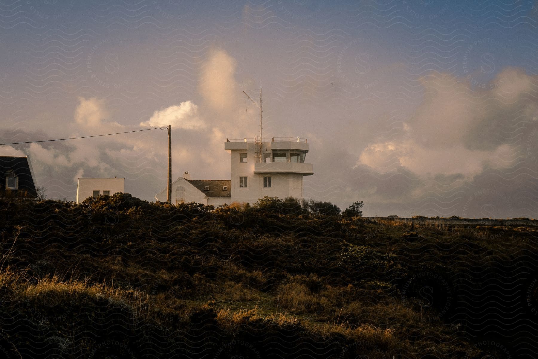 White house on top of hill stands against cumulus clouds.