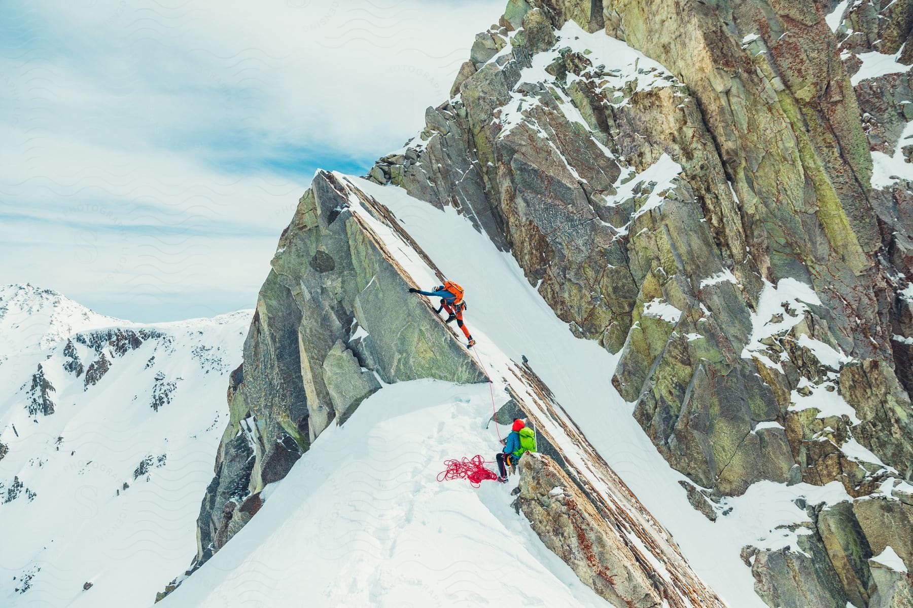 Two people climbing mountains completely covered in snow.