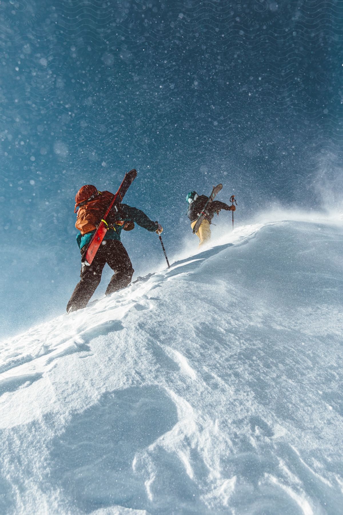 Two people climbing a snow-covered mountain with ski and snowboard equipment.