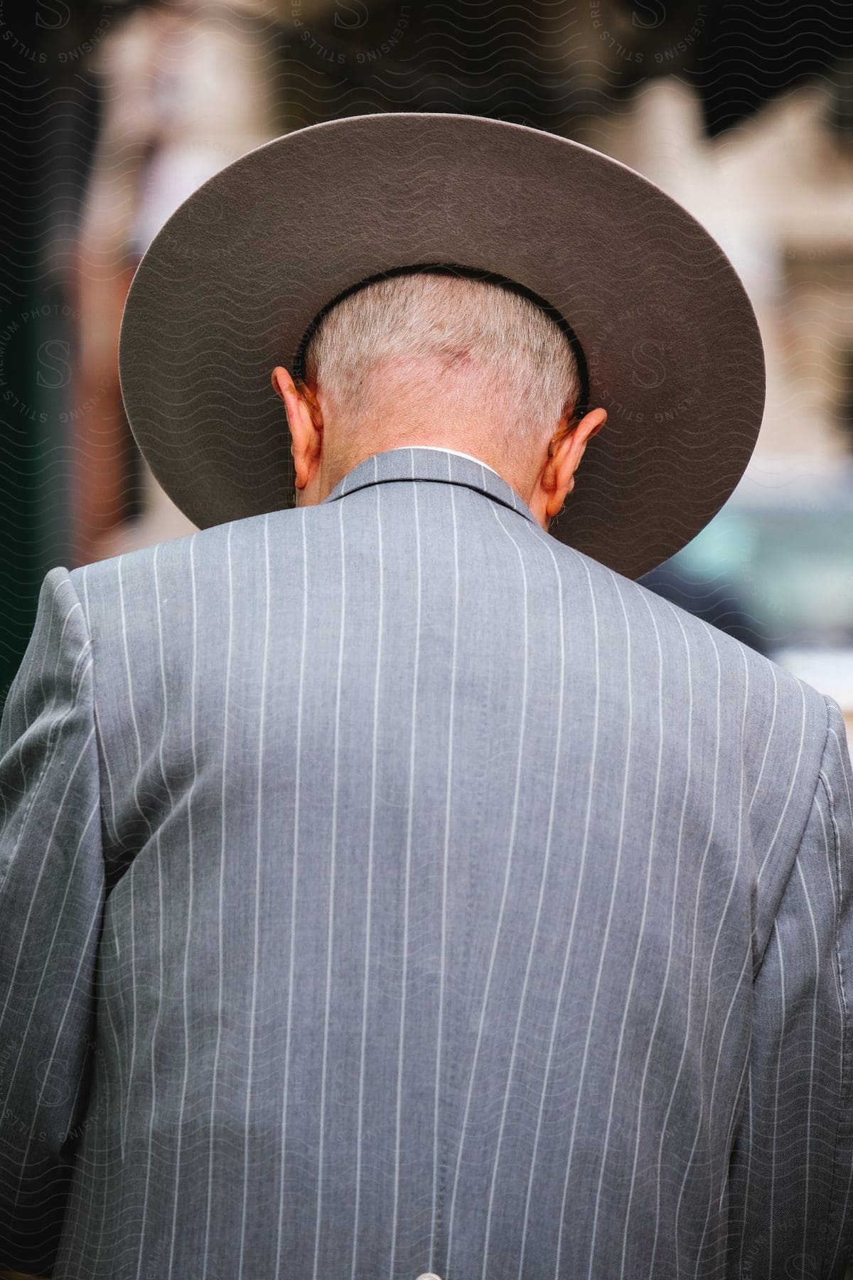 Elderly man from the back wearing hat and suit.