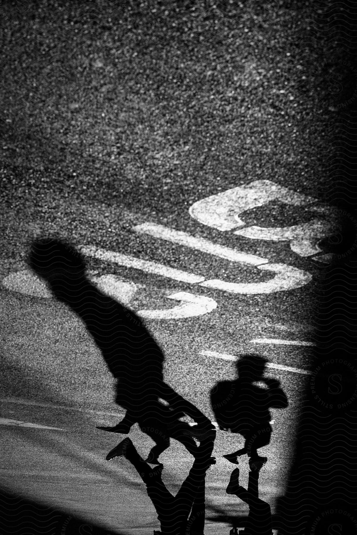 Silhouette And Shadows Of Two People Walking Down The Street