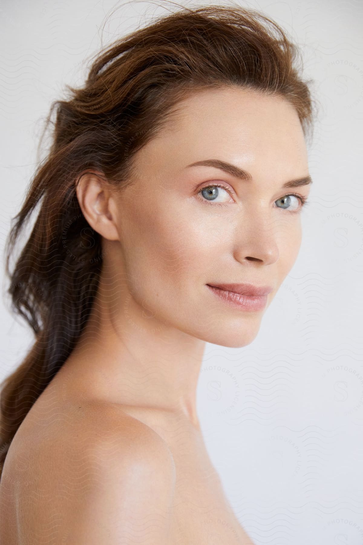 A brunette woman with medium-length hair and bare shoulders with blue eyes