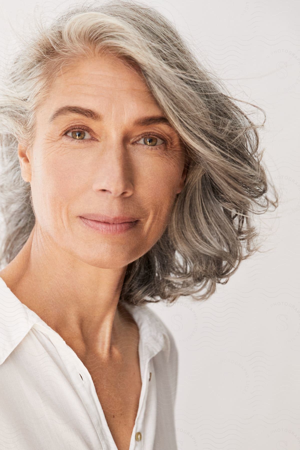 A woman with gray hair and brown eyes is looking ahead