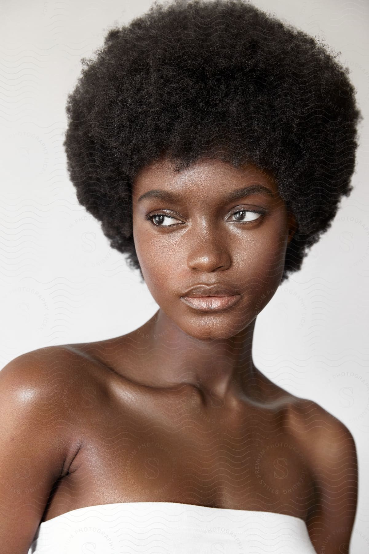 A bare shouldered woman with an afro is looking to her side