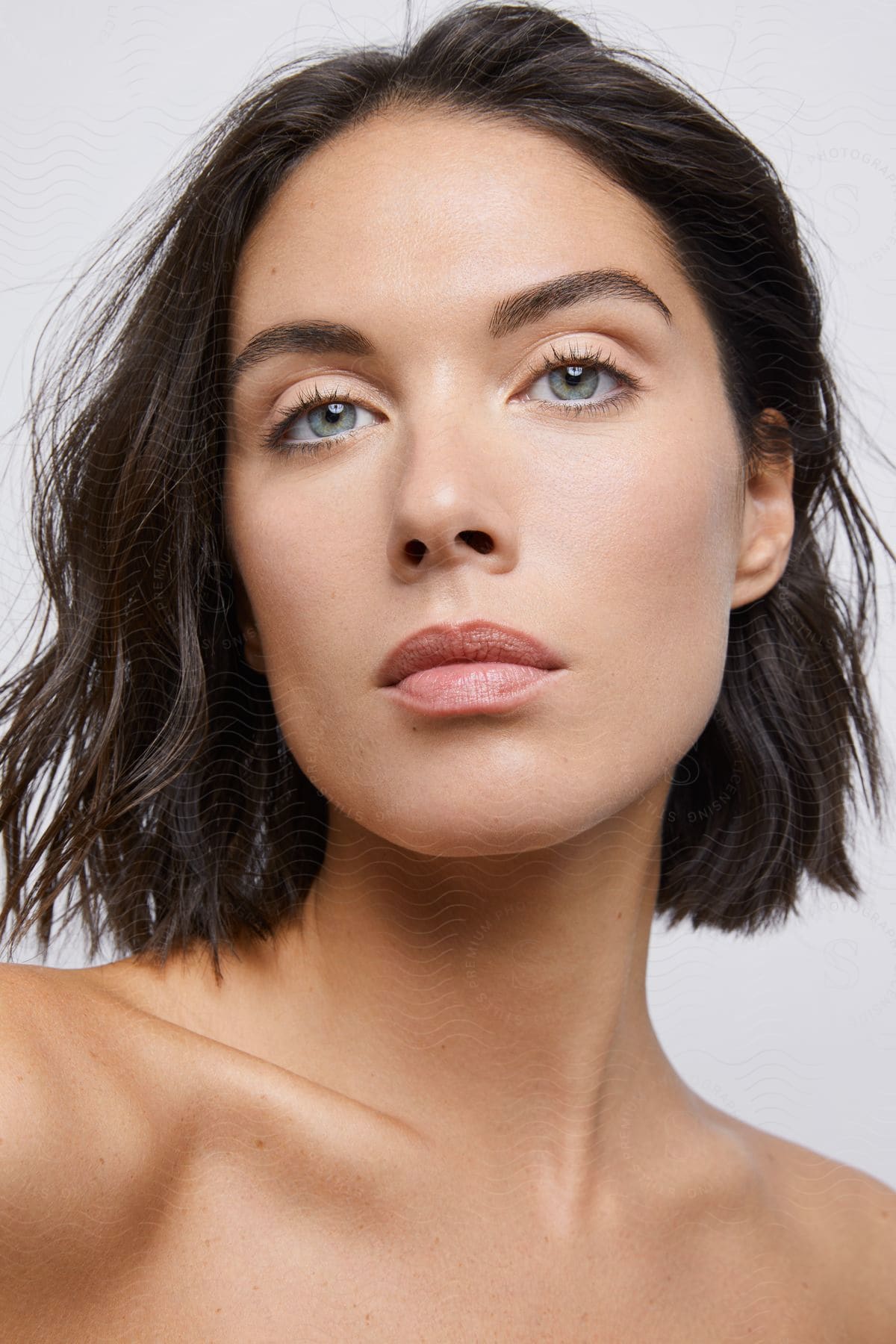 A close-up head-shot of a young woman with short, shoulder-length brown hair with blue eyes.