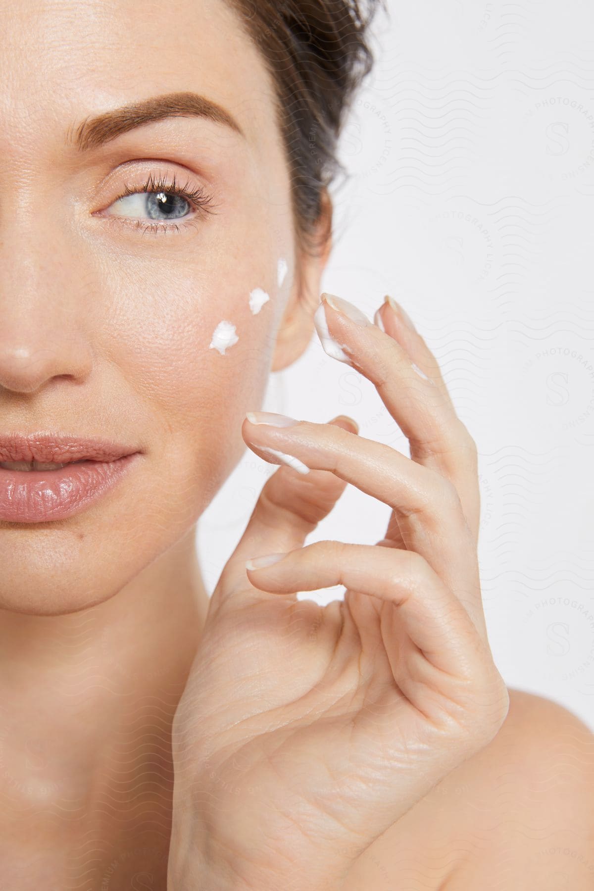 Close-up of woman using facial moisturizer.