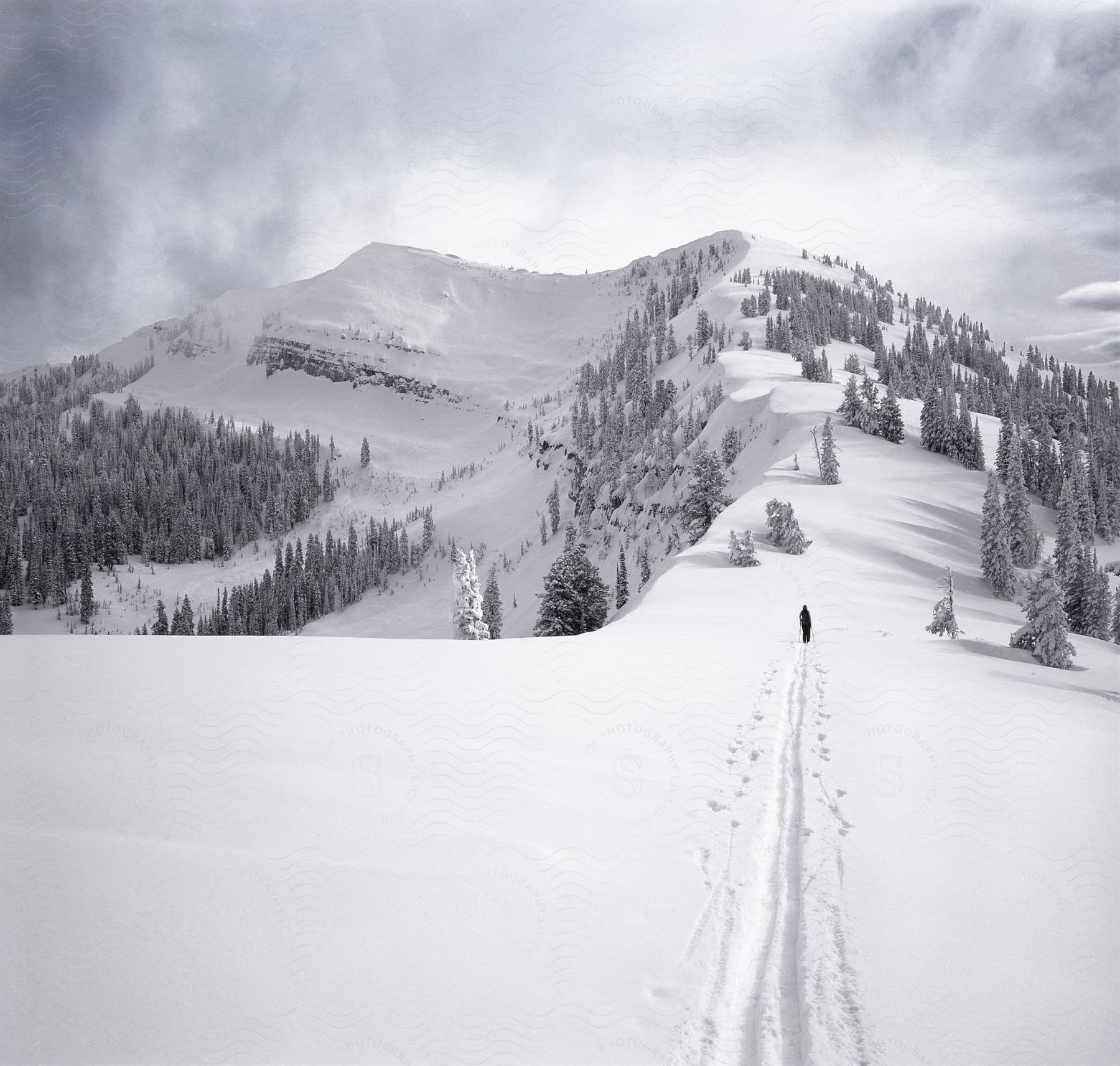 a person walks through thick snow at the base of a mountain