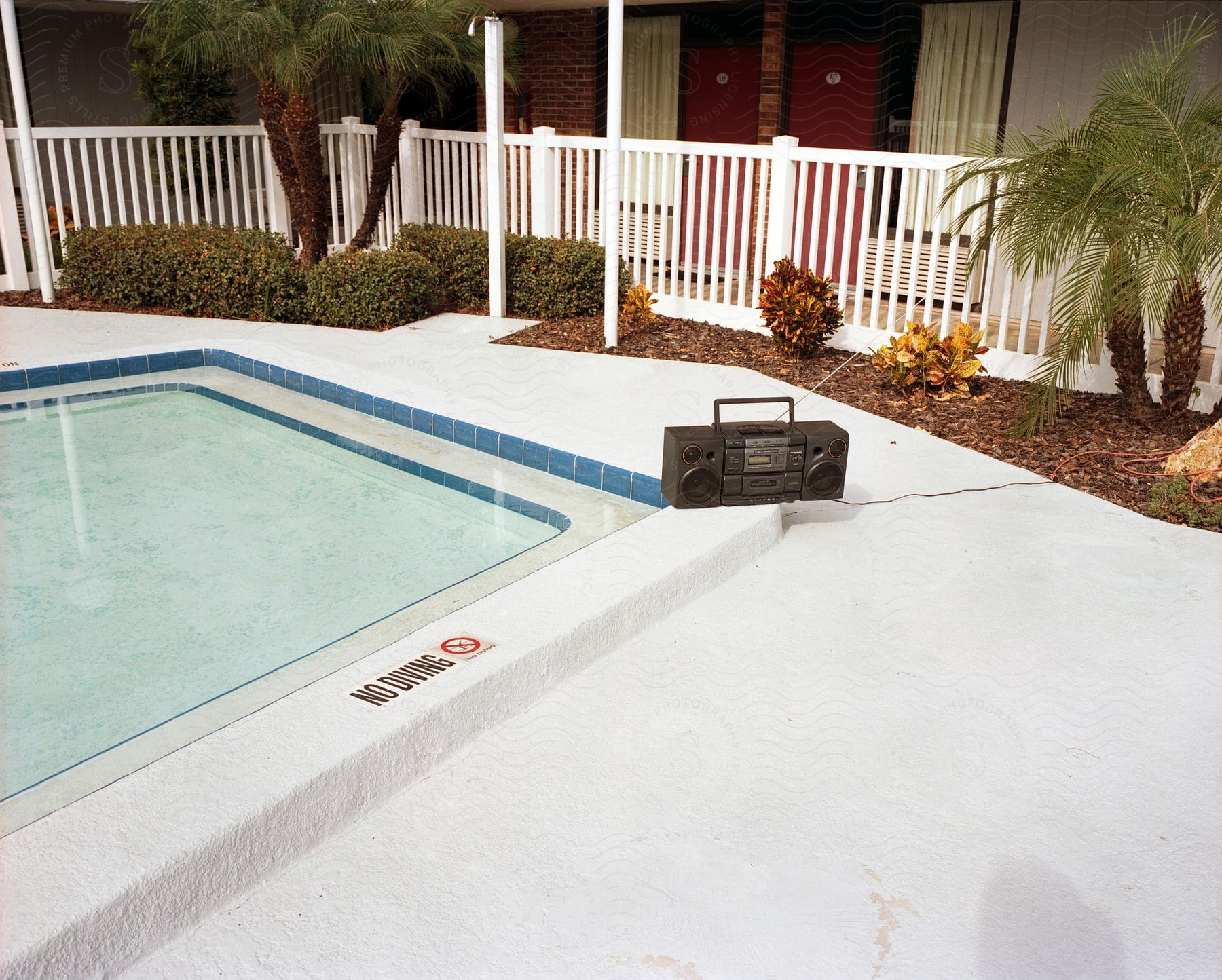 A boom box sits next to a hotel swimming pool.