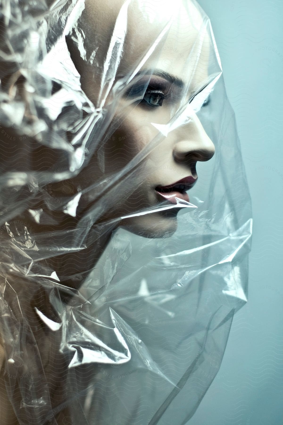 A highly detailed mannequin with a realistic face is covered in a plastic bag