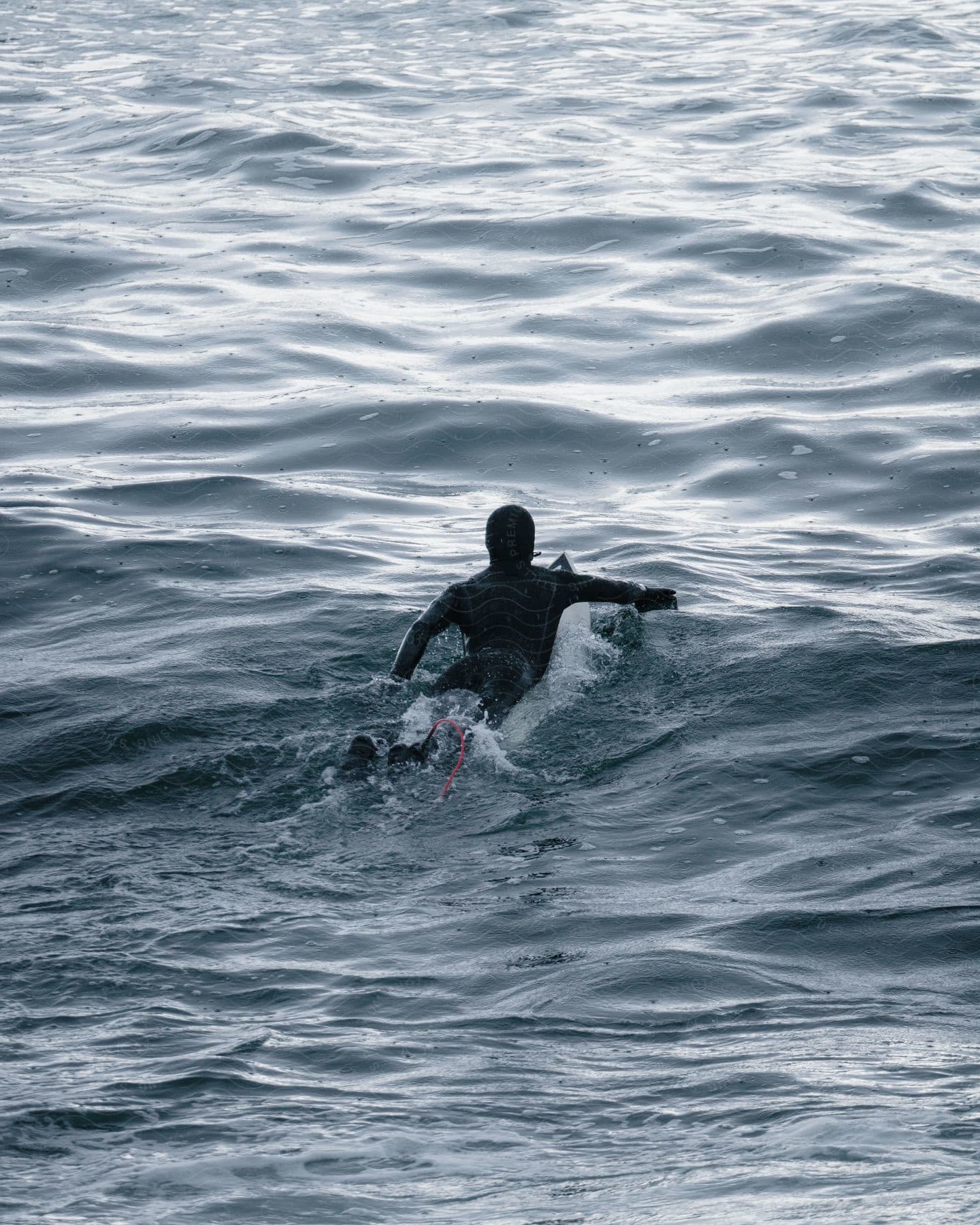 Man paddling with the surfboard in the sea.