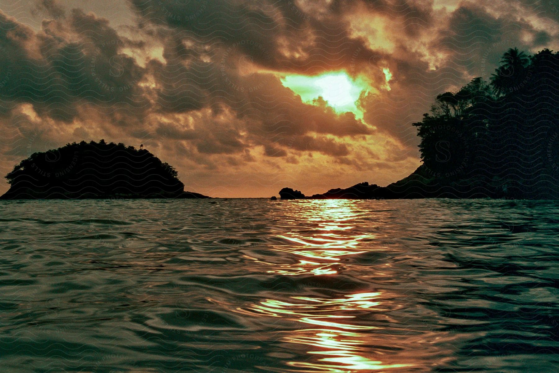 Sunrise over ocean with rocks and shore.