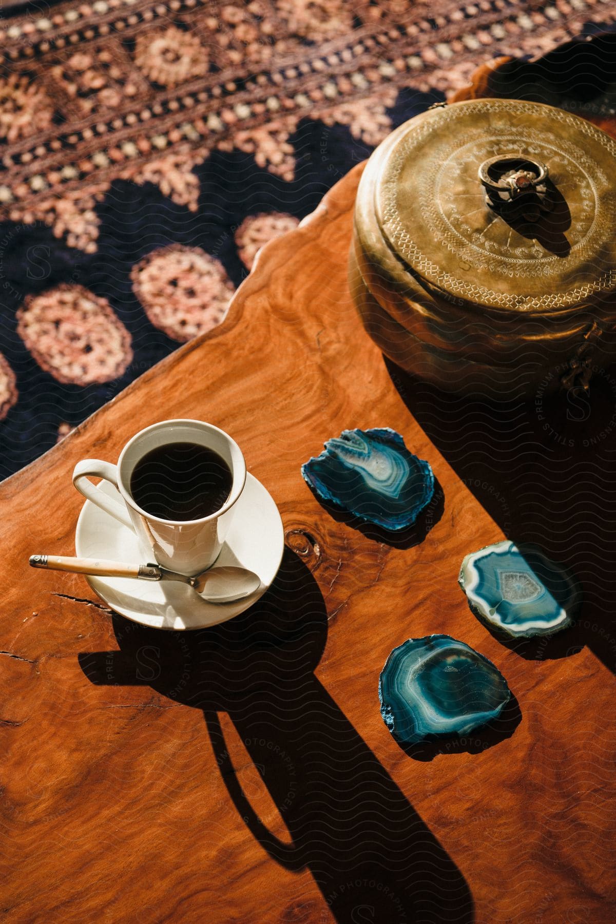 A coffee cup is located on a wooden table next to some stone coasters.