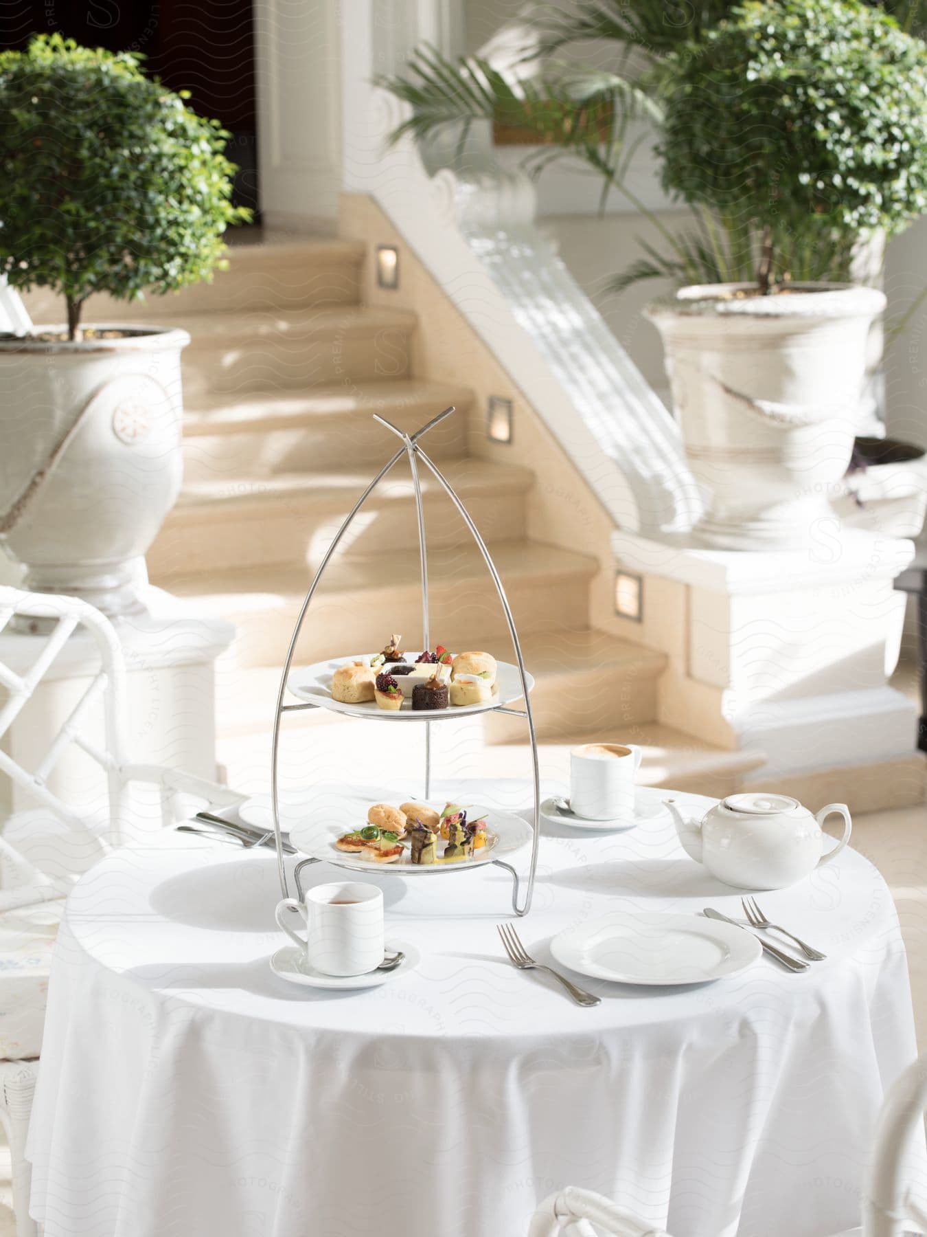 A table is set outside for two with tea and a few light snacks on a white table cloth.