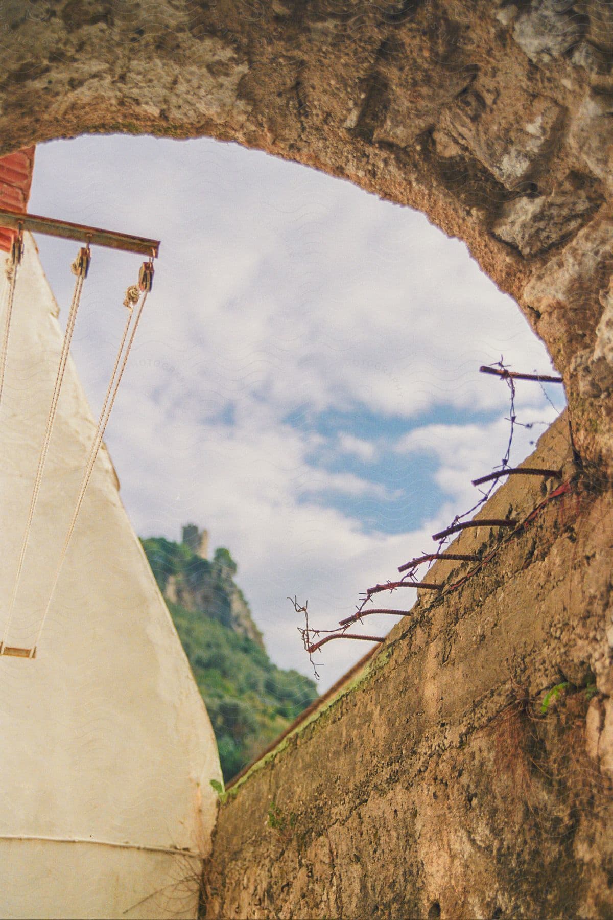 A wall and a tunnel of old stones and some rusty iron on top.