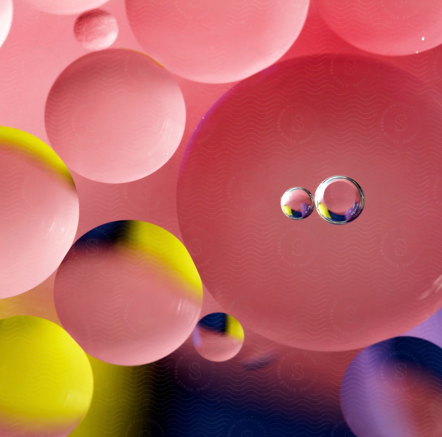 Small transparent bubbles in front of pink and yellow balls.