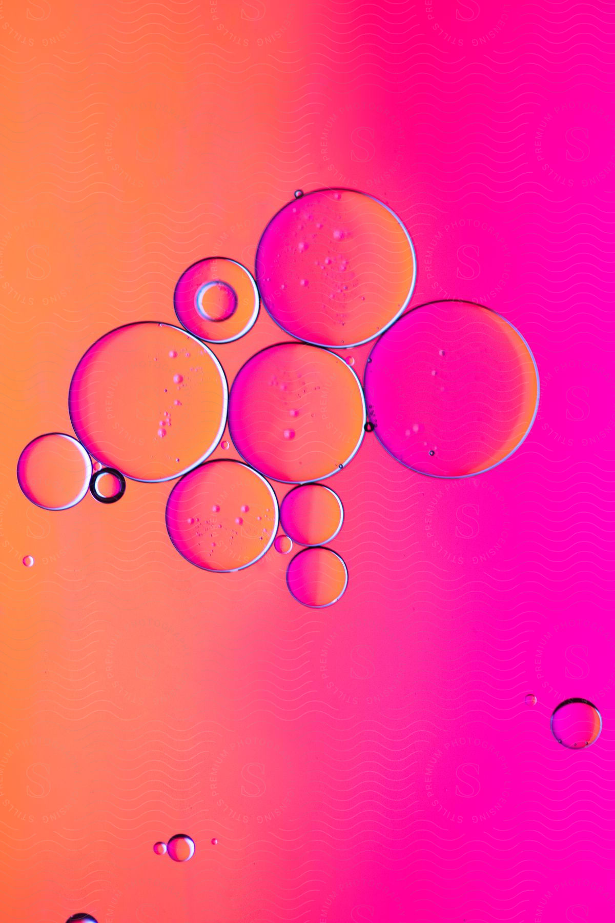 Several transparent bubbles forming a cluster on a colorful orange and pink background.