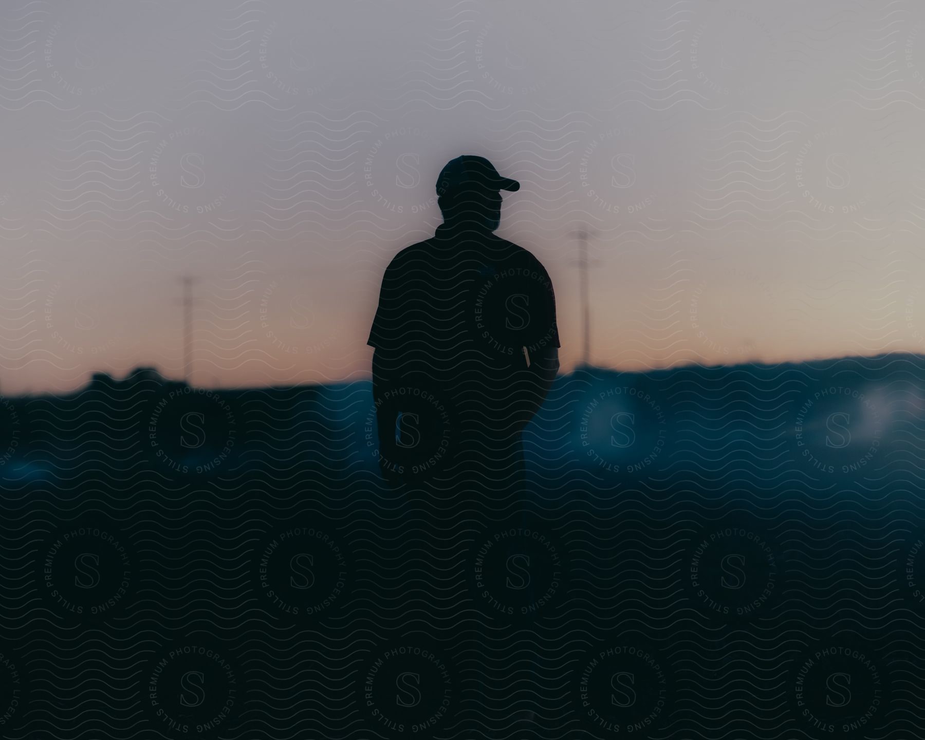 Stock photo of a man in a baseball cap stands in the fog-shrouded darkness of a grassy field.