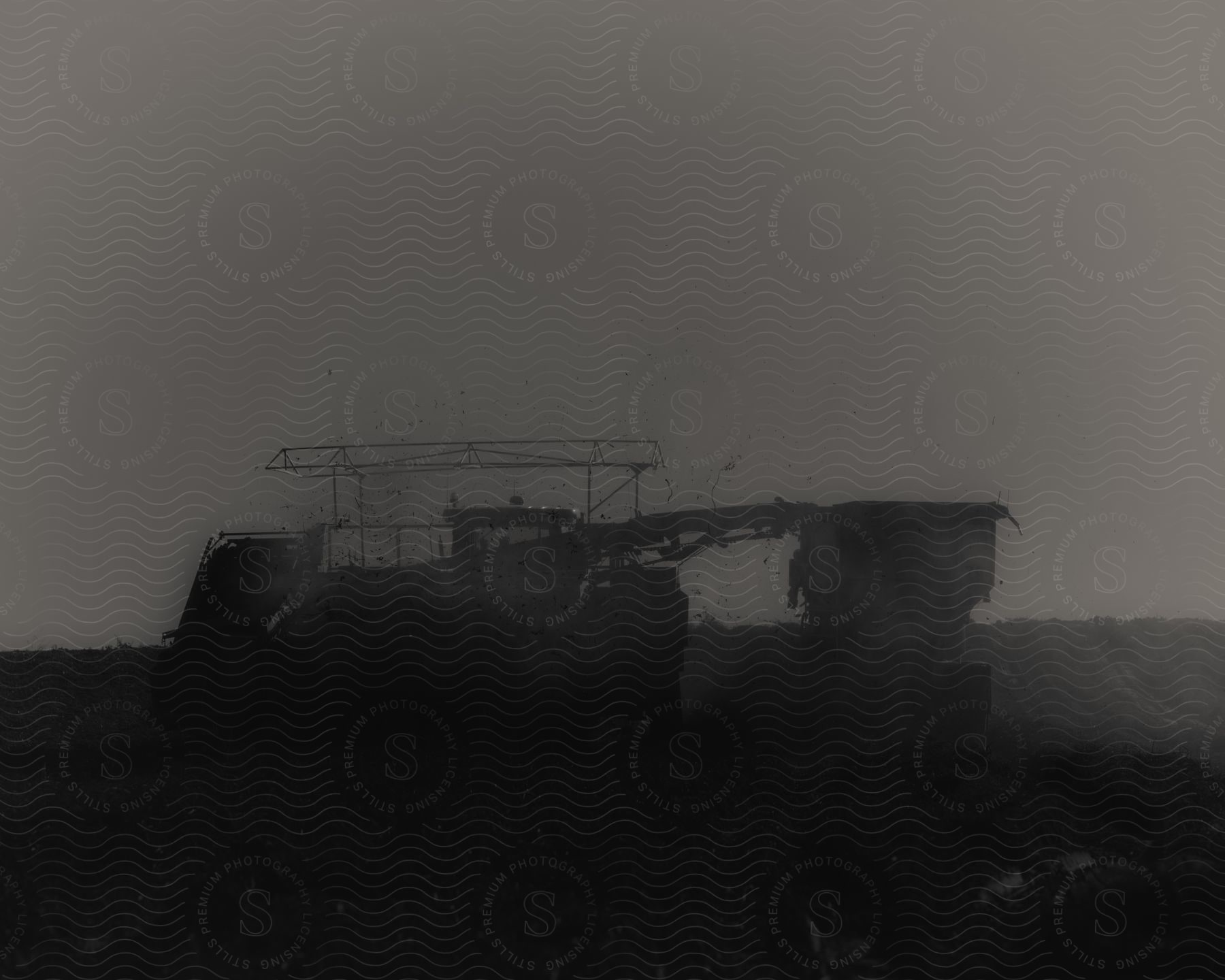 Stock photo of an old harvester machine driving in a field in black and white