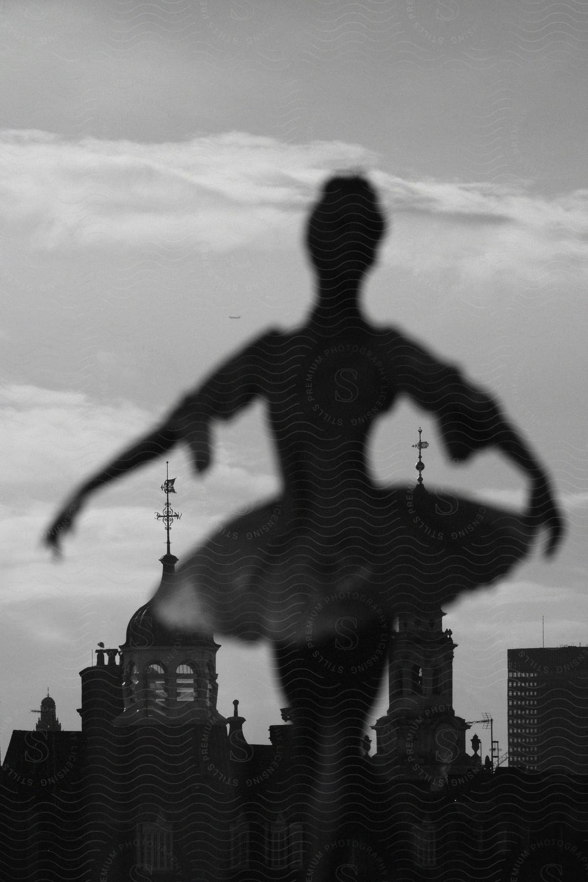 A dancer is performing a ballet move with the view of buildings.