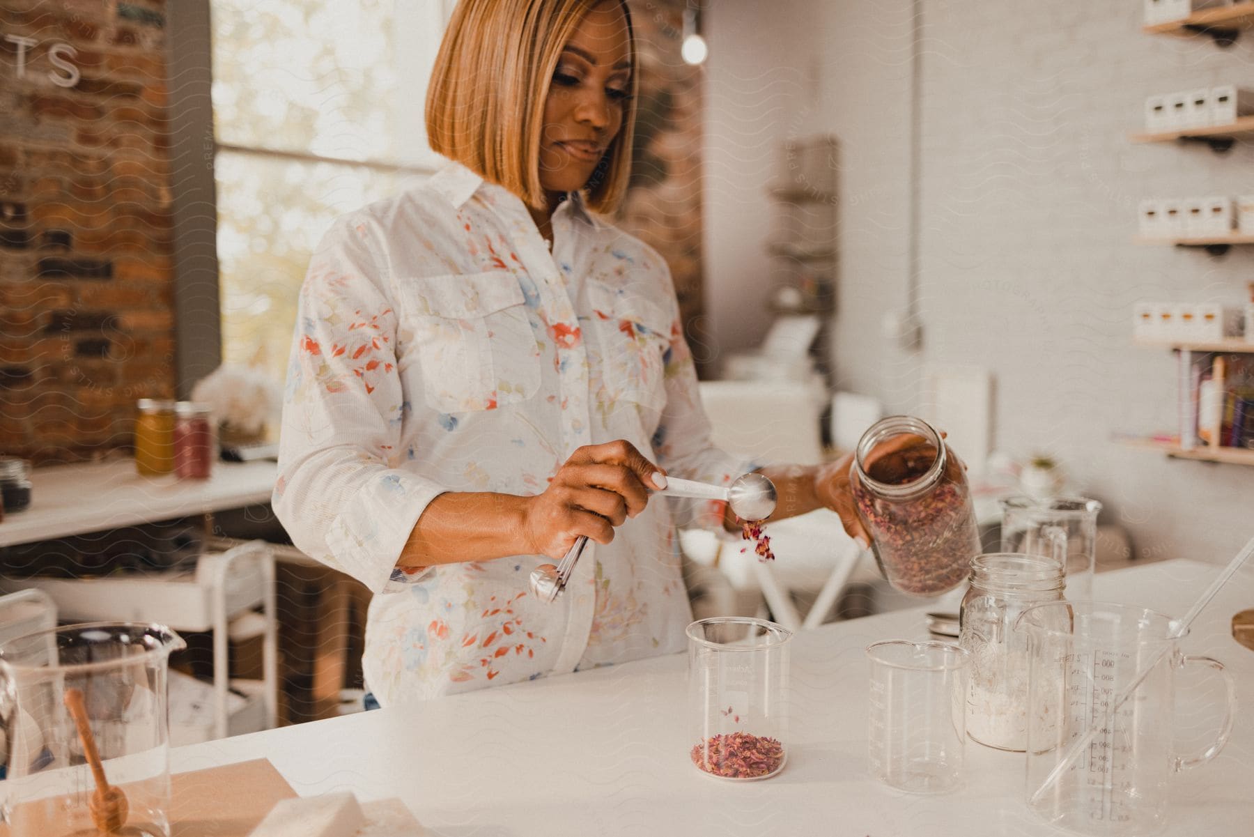 A young woman is standing in a kitchen and measuring ingredients into a flask.