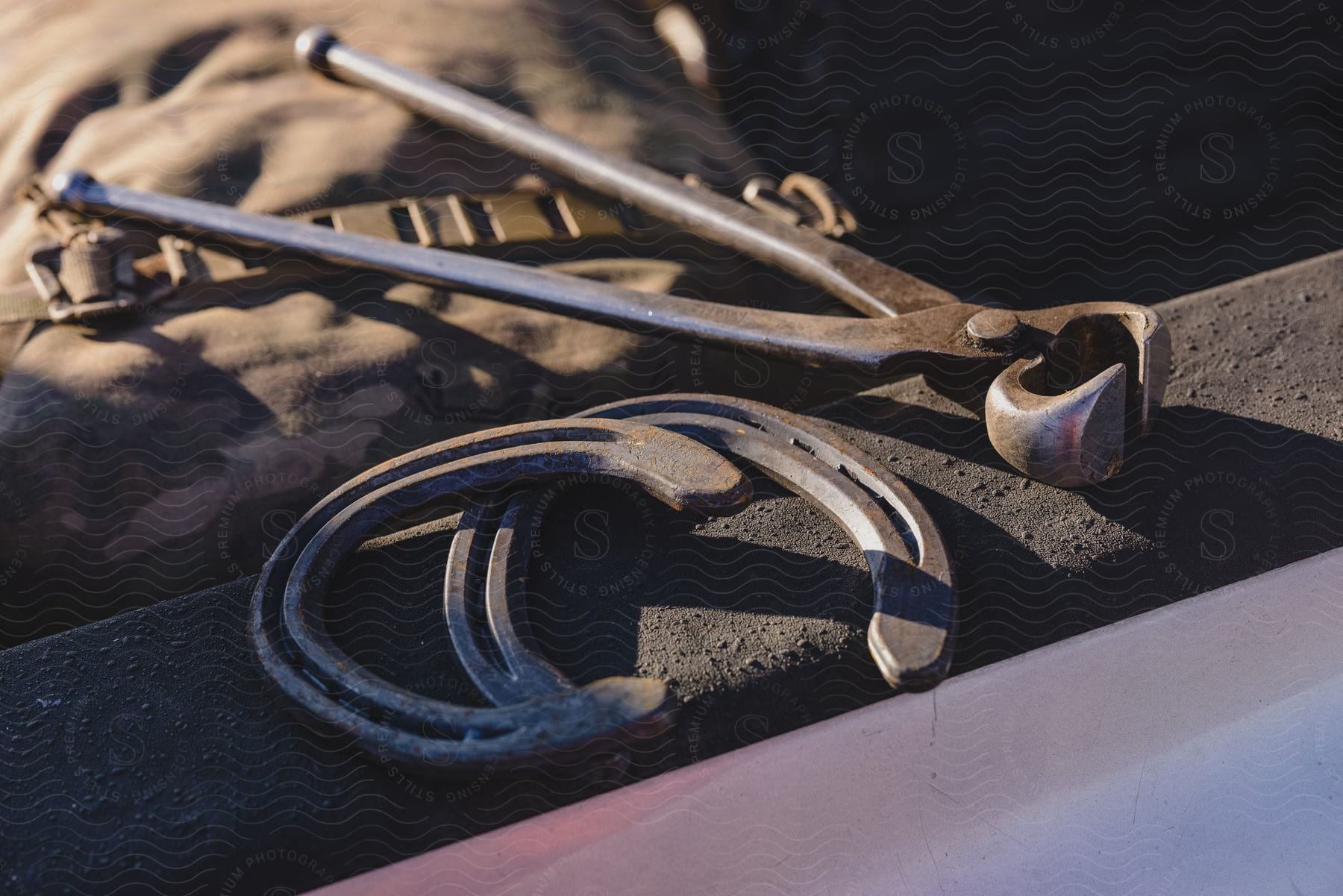 A horseshoe and a tool on top of a dirty platform.