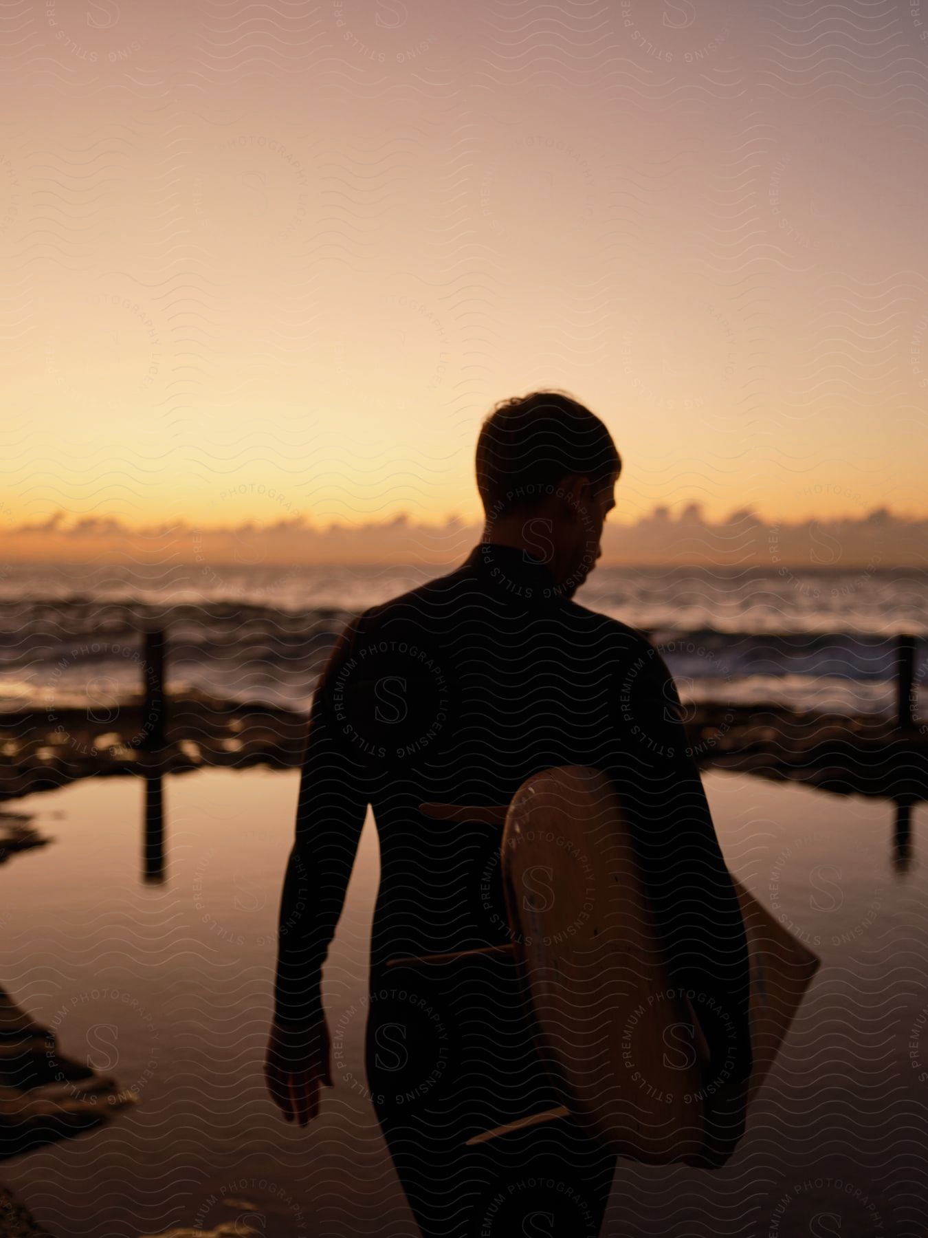 Surfer walking into the sunset.