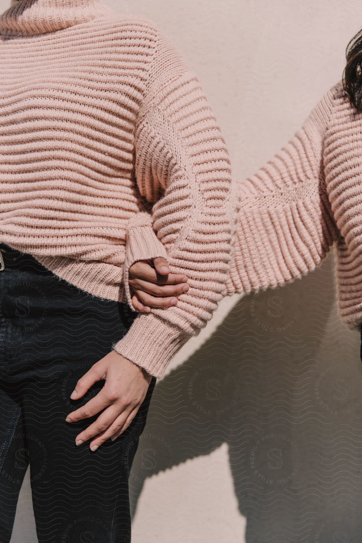 Two women stand together while wearing matching knitted sweaters.