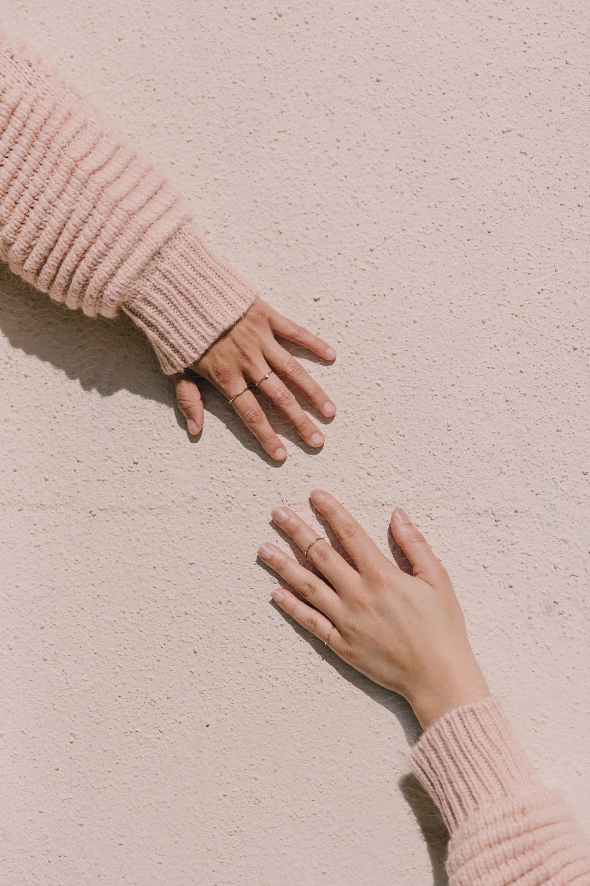 Two Women Wearing Matching Knitted Sweaters Hold Their Hands Out Towards Each Other