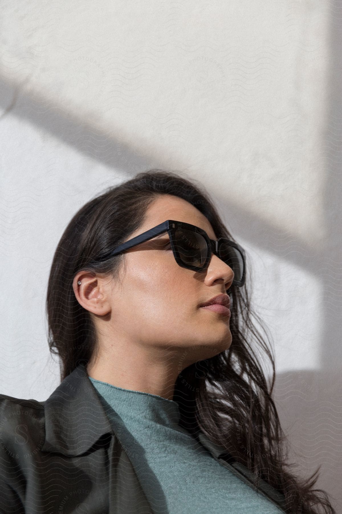 Woman with dark hair black sunglasses and blazer jacket looks up and smiles