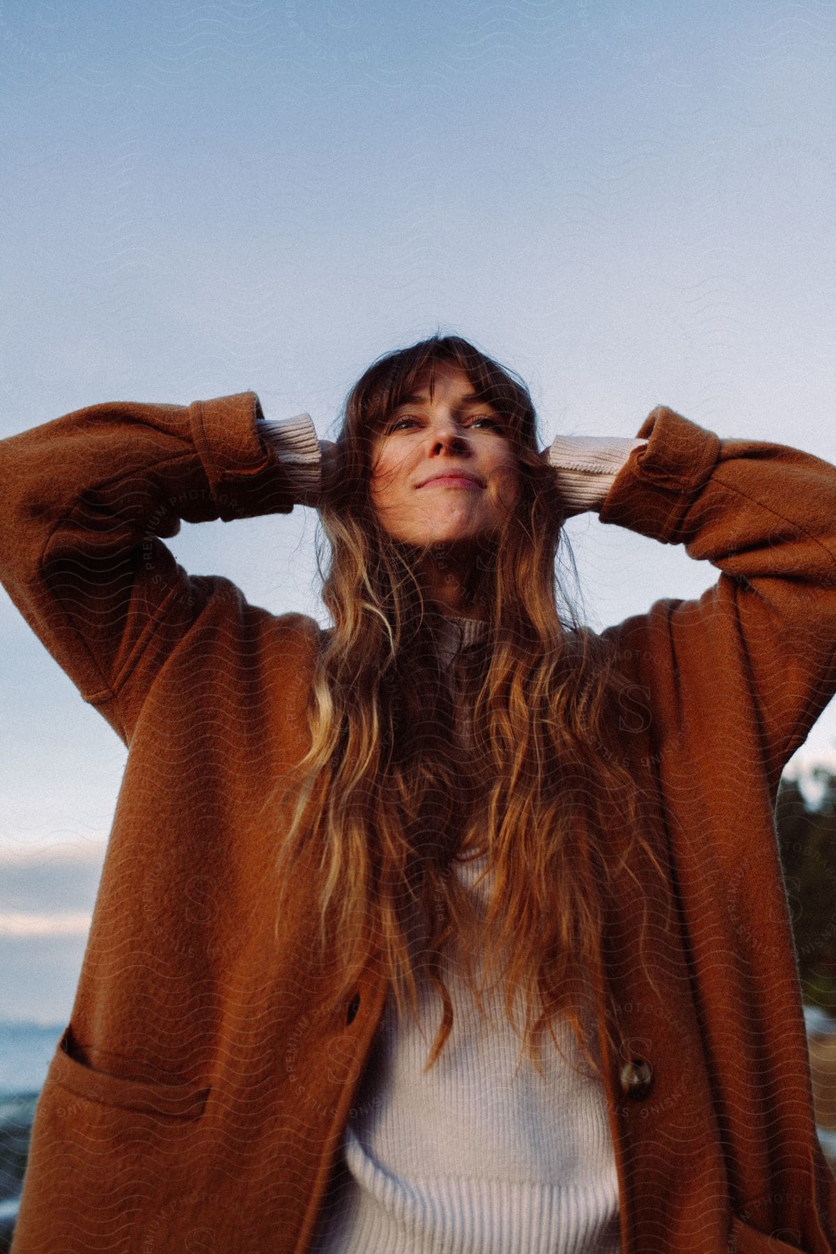 Portrait of a woman with her hands on her head and a facial expression of happiness.