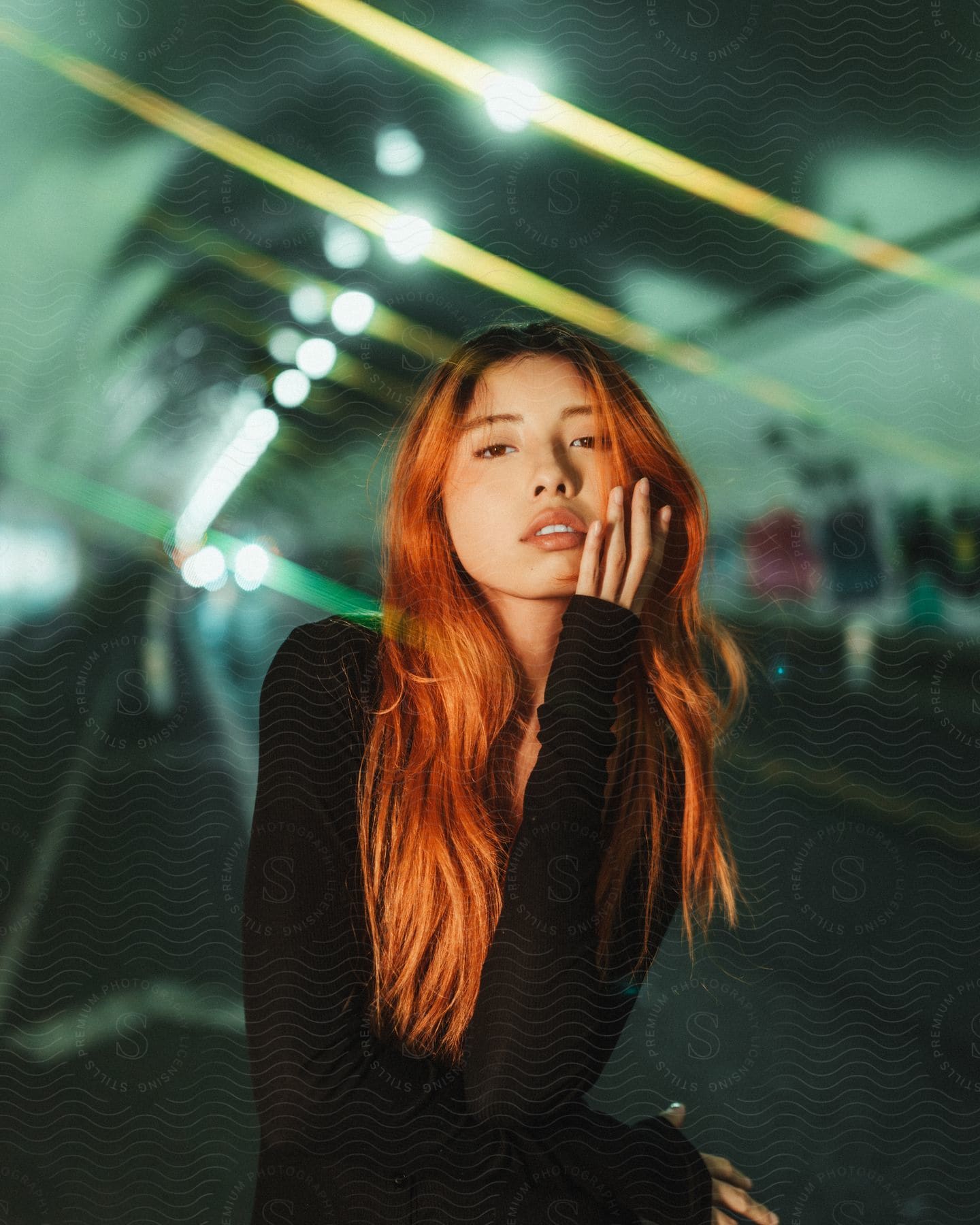 An Asian woman with long red hair stands in a transportation tunnel.