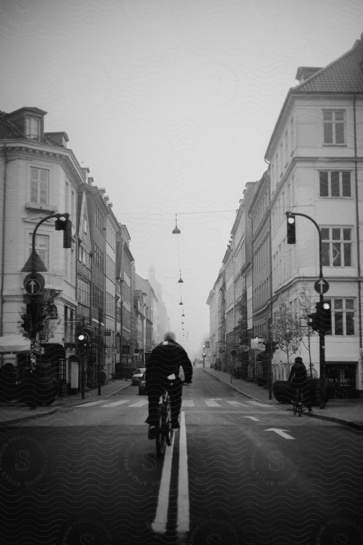 Two people are riding bicycles on a downtown street lined with tall buildings