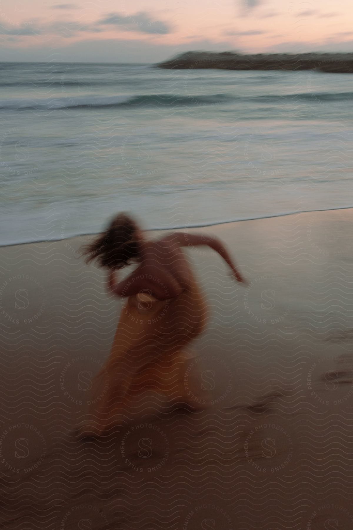 A lady dances around the beach as her hair swings back and forth.